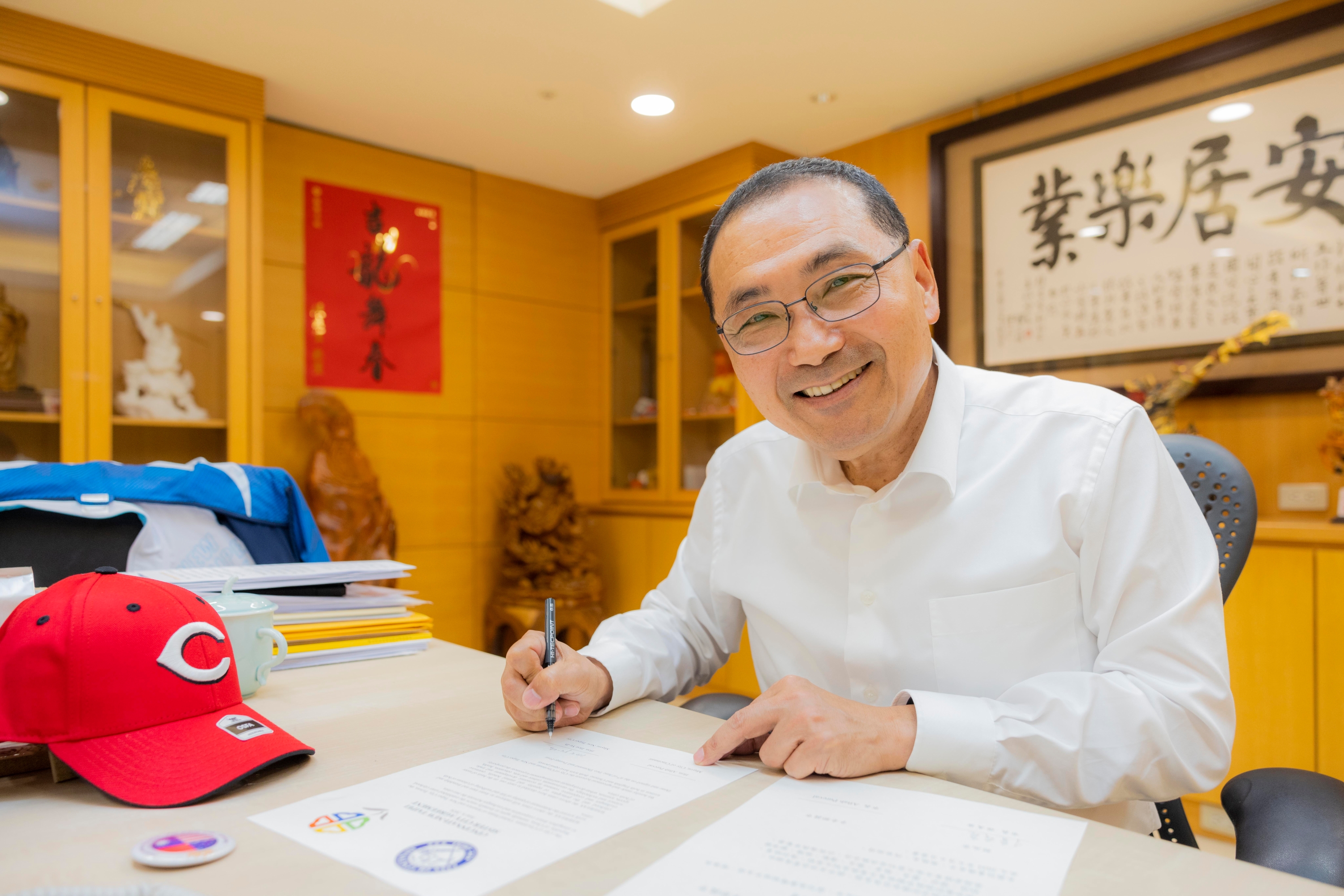 New Taipei City Mayor Hou Yu-ih is delighted to renew the sister city agreement with Cincinnati, and, as a sports enthusiast, he unboxes a Cincinnati Reds baseball cap.